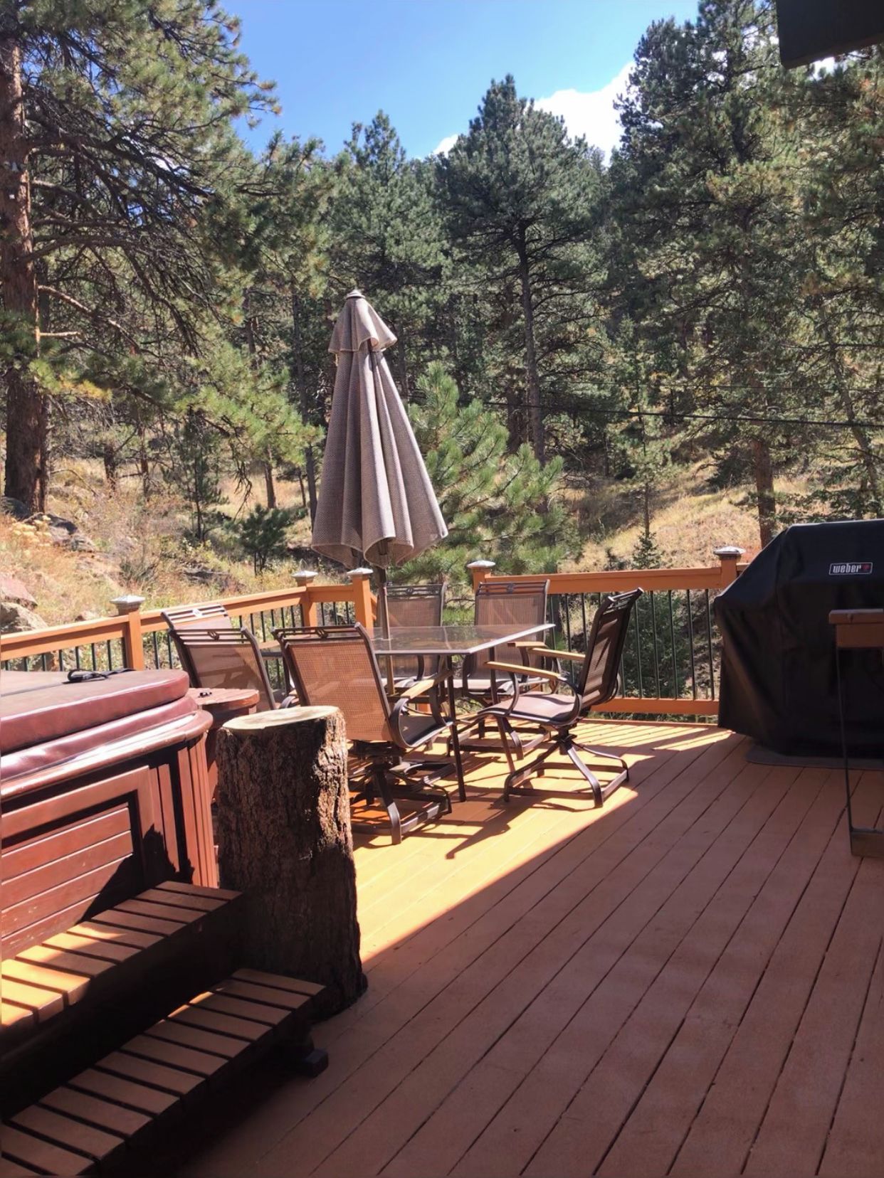 A wooden deck with outdoor furniture, including a table and chairs, and a grill.
