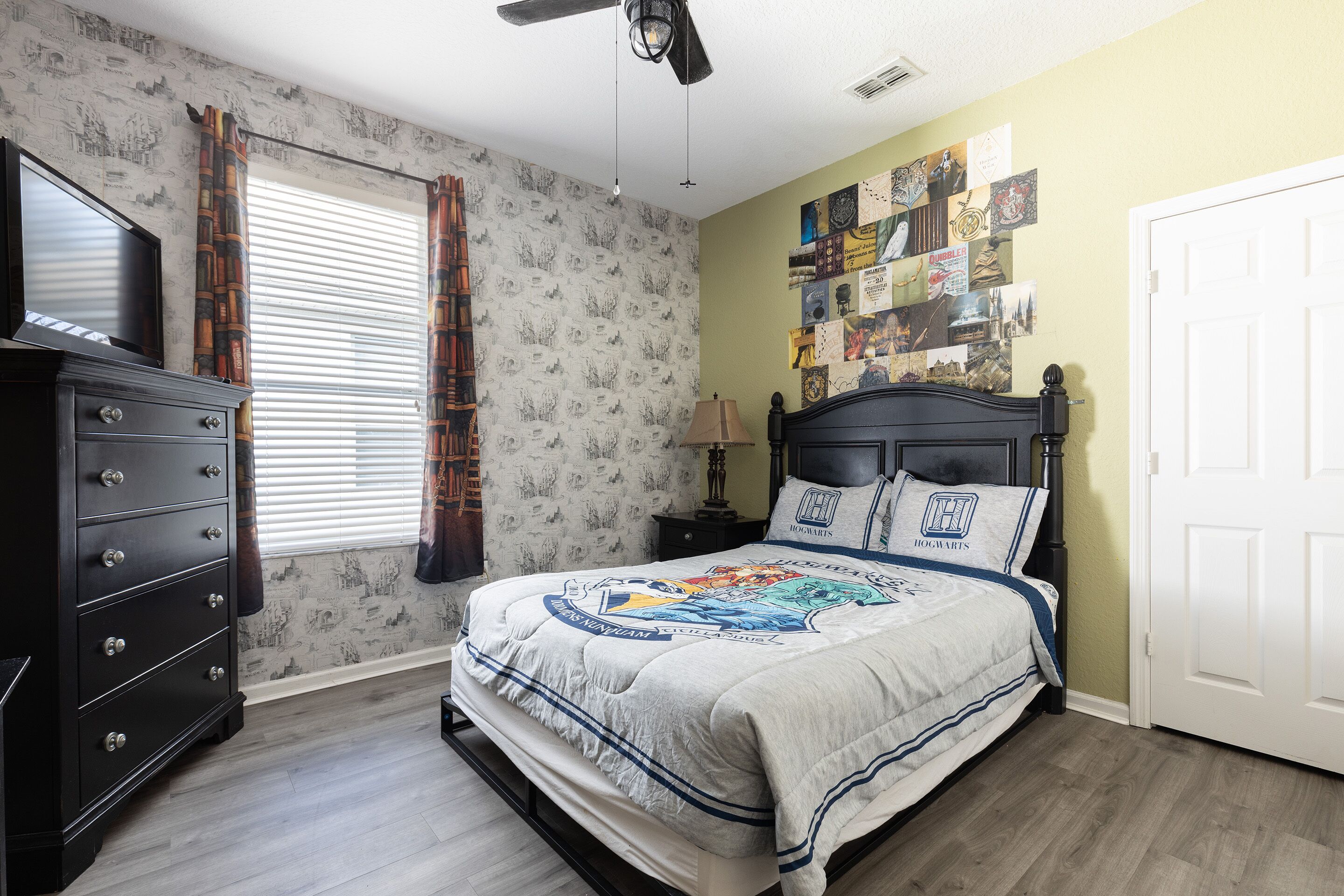 A bedroom with a bed, dresser, and a wall with photos.