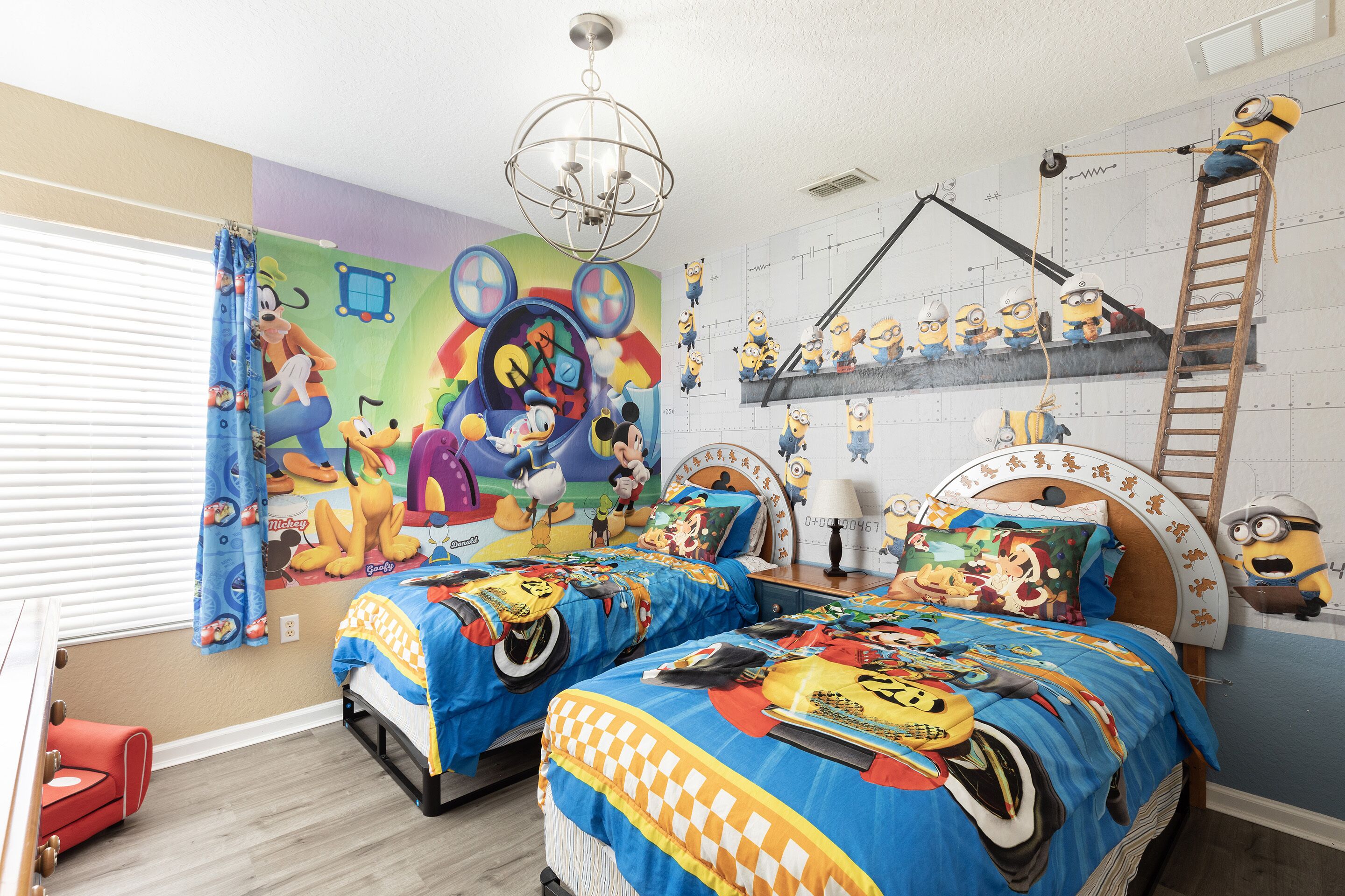 A children's bedroom with two beds, a mural, and Minion-themed decorations.