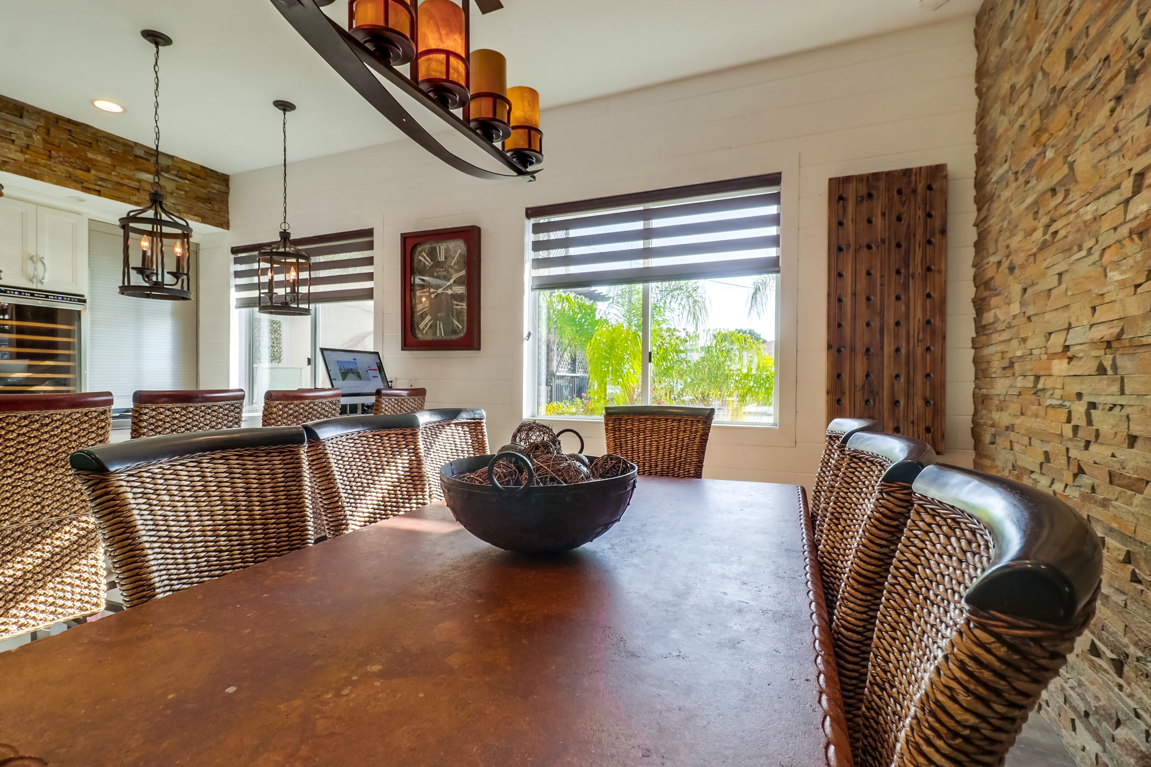 Un coin repas avec une grande table en bois, des chaises en osier et un panier de gressins.