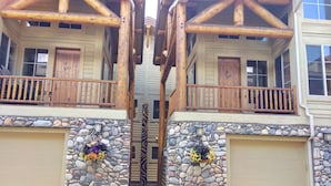 A two-story building with a stone facade, wooden balconies, and a central staircase.