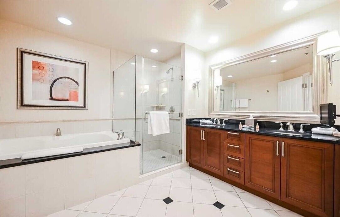 A modern bathroom with a large bathtub, a glass-enclosed shower, and wooden cabinets.