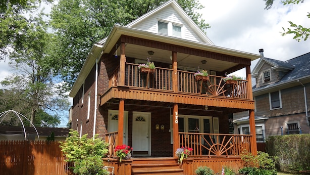 A two-story house with a wooden porch, a front door, and a number '170' on the side.
