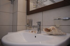 Chuveiro, secador de cabelo, toalhas de banho, papel higiênico