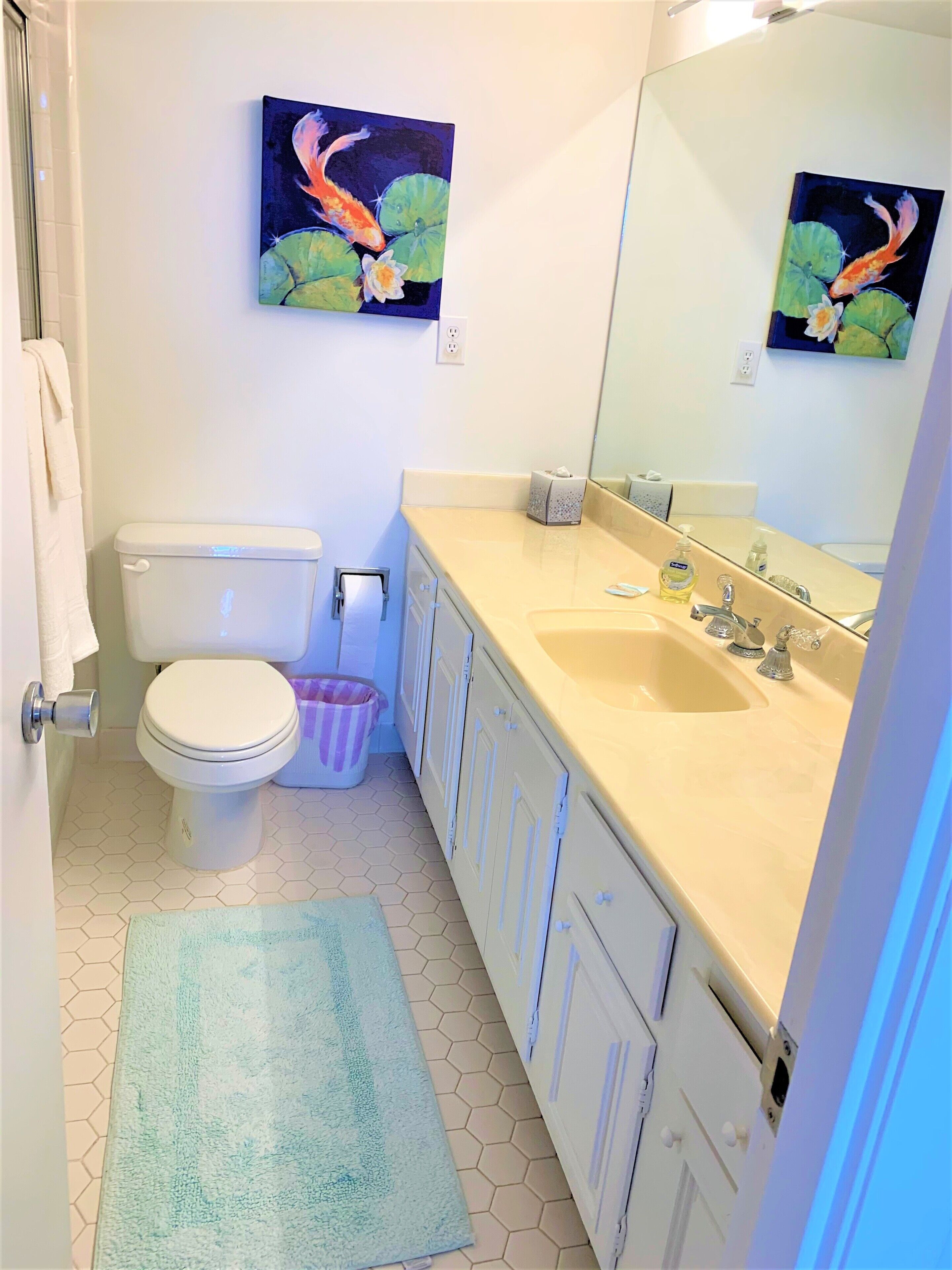 Une salle de bain avec des toilettes, un lavabo et un tableau représentant des carpes koï au mur.