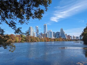 Stadszicht met moderne wolkenkrabbers, een rivier op de voorgrond en herfstkleuren.