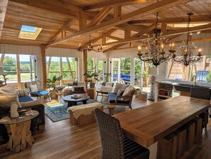 Un vaste espace de vie agrémenté de poutres en bois, d’une grande table en bois et de sièges confortables.