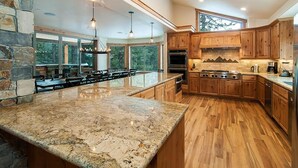 A spacious kitchen with granite countertops, wooden cabinets, and a large island.