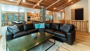 A spacious living area with a black leather sectional sofa, a coffee table, and a stone pillar.