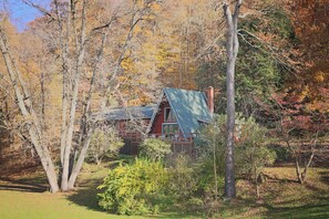 A cabin surrounded by trees with autumn foliage.
