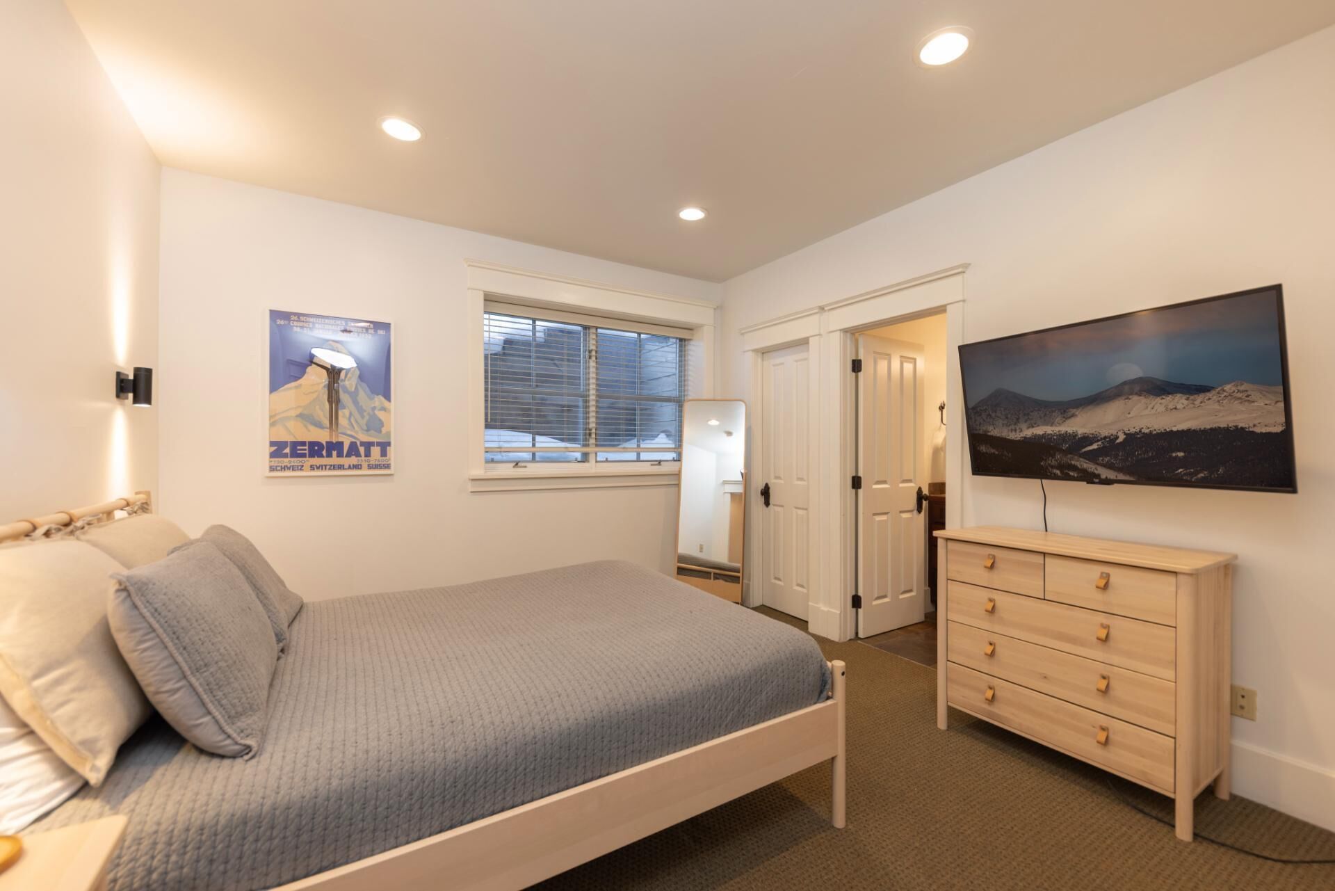 A bedroom with a bed, dresser, and a large window.