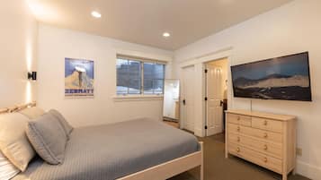 A bedroom with a bed, dresser, and a large window.