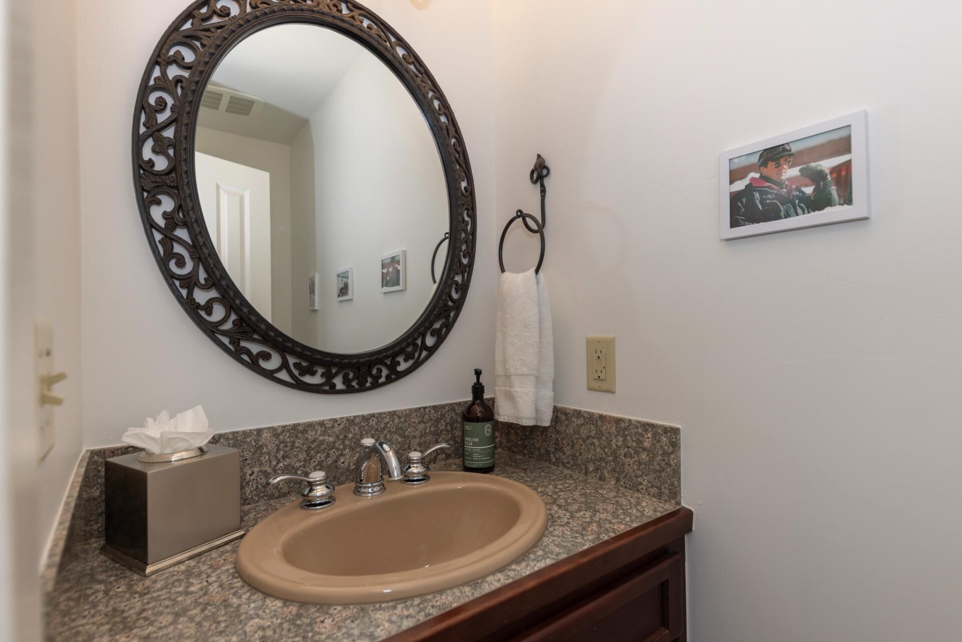 Un baño con un espejo redondo, un lavabo y un perchero para toallas.