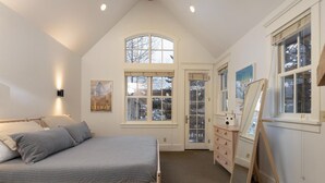 Un dormitorio con cama, cómoda, espejo y ventana con vista al exterior.