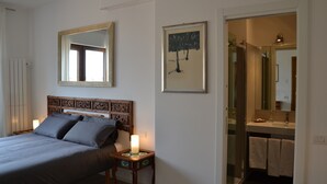 A bedroom with a bed, bedside table, nightstand, and a mirror on the wall. - STUDIO WITH VIEW NEAR THE COLOSSEUM (Roma)