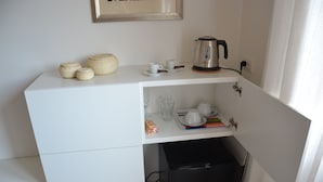 A compact kitchenette with a coffee maker, cups, and a small refrigerator. - STUDIO WITH VIEW NEAR THE COLOSSEUM (Roma)