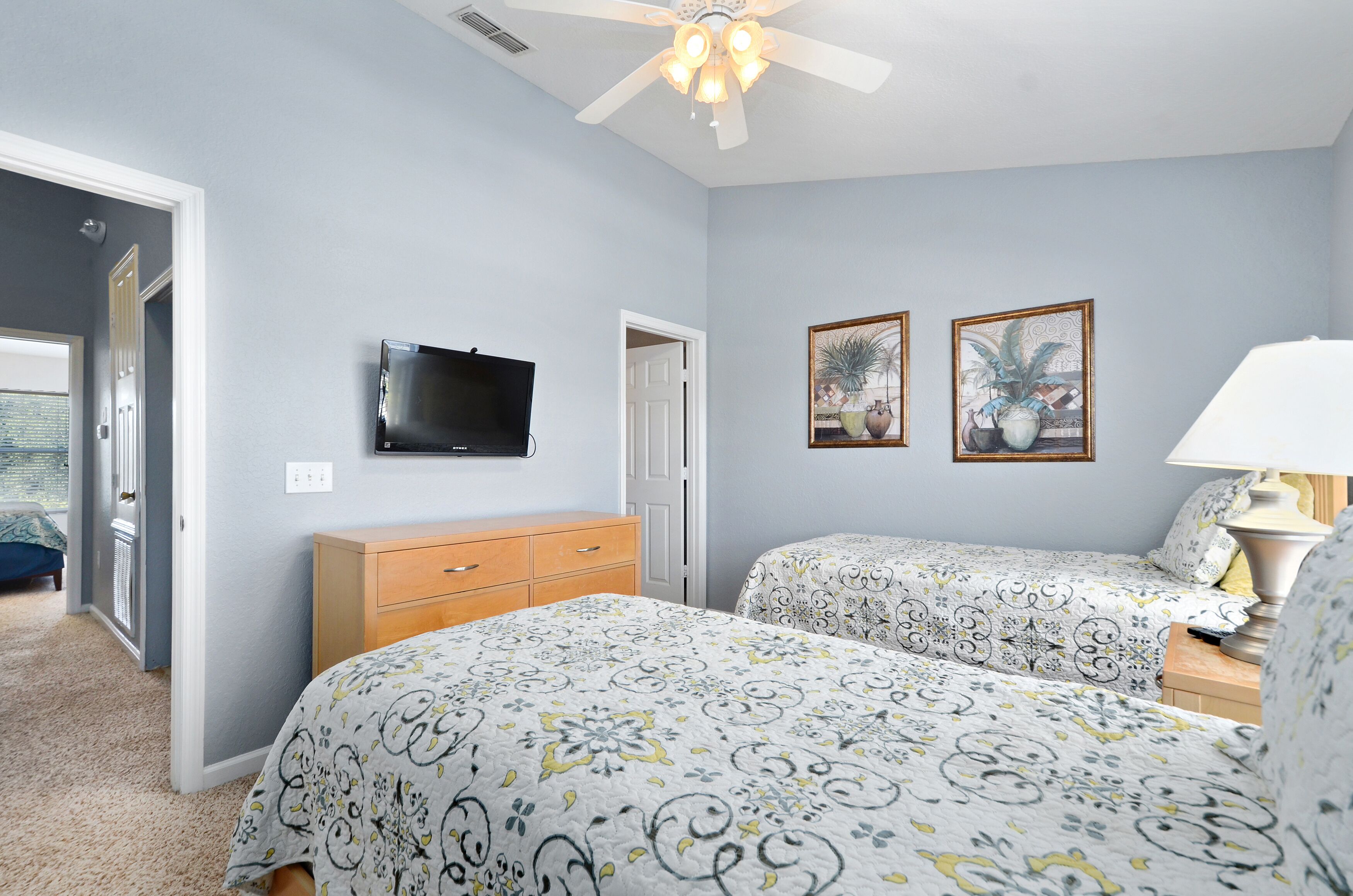 A bedroom with two beds, a TV, and a ceiling fan.