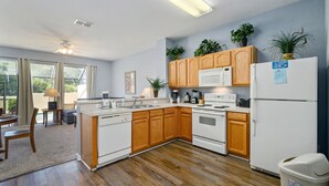 Une cuisine moderne avec des meubles en bois, un réfrigérateur blanc et un four encastré.