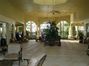 Relax in a spacious area with a high ceiling, surrounded by lush greenery and a large potted plant.
