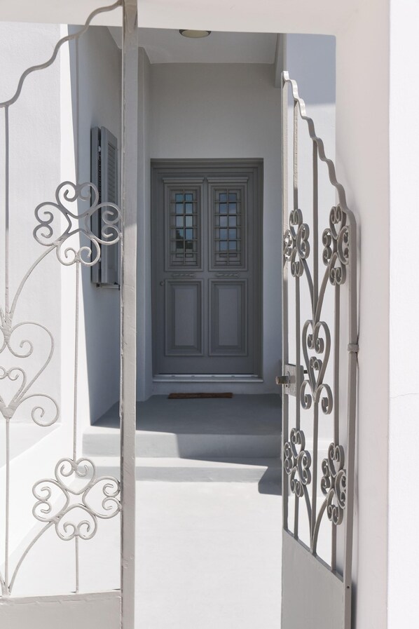 A white door with a decorative metal gate, leading to a staircase. - Villa DALI Danae with large jacuzzi and unique volcano and caldera view (Thira)