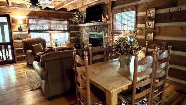 A rustic cabin interior with a wooden dining table, chairs, a sofa, and a fireplace. - Beautiful Real Log Cabin.... Not your average cabin! Hot Tub. Wifi. Fire Pit (Blue Ridge)
