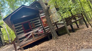 A rustic cabin with a stone chimney, wooden deck, and a red door. - Beautiful Real Log Cabin.... Not your average cabin! Hot Tub. Wifi. Fire Pit (Blue Ridge)