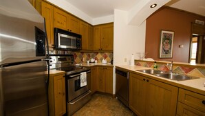 A kitchen with wooden cabinets, stainless steel appliances, a tiled backsplash, and a sink.
