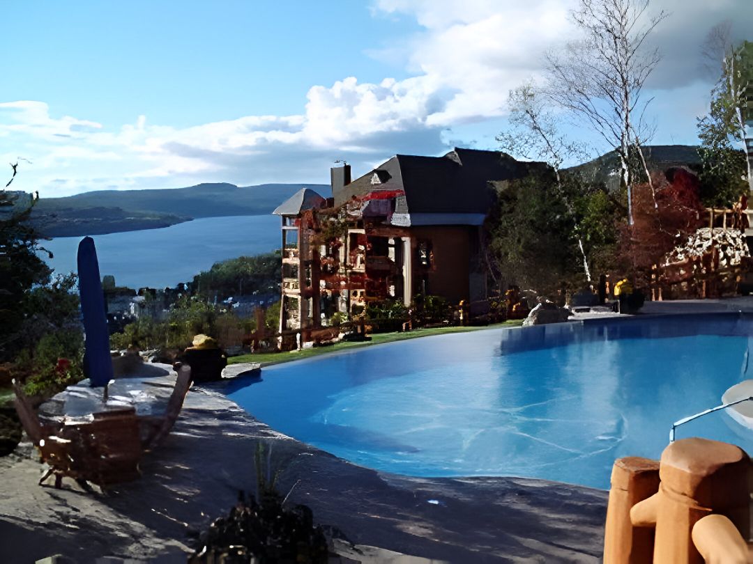 A swimming pool area with a view of a lake and a building with multiple balconies.
