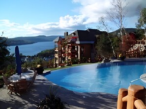Un espace piscine avec vue sur un lac et un bâtiment doté de nombreux balcons.