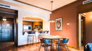 A modern kitchen with a central island, bar stools, and a dining table.