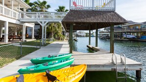 Un muelle con kayaks, una zona de estar cubierta y vistas al agua.