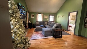 Ein Wohnzimmer mit einer Eckcouch, einem Weihnachtsbaum und einem flachbildfernseher an der Wand.