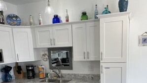 A modern kitchen with white cabinets, a wooden island, and various kitchen appliances. - 🏖️GROUND FLOOR UNIT 🏖SUNSET COTTAGES😎PETS WELCOME🐾
FREEBEACHSERVICE/WI-FI  (Fort Walton Beach)