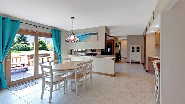A modern kitchen with a central island, a dining area with chairs, and a view through the glass door. - Superb British Colonial holiday home, greenhouse, outdoor deck, tropical garden (Barboursville)