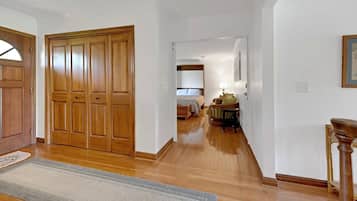 Un couloir avec un plancher en bois, une grande porte en bois et un lit à l’arrière-plan.