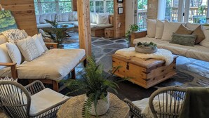 A cozy cabin interior with a stone floor, wooden furniture, and large windows offering views of the outdoors. - Parkside INCREDIBLE location-VIEWS-Kayak, SUP, Pool, Gorgeous Hikes-Restaurants (Austin)