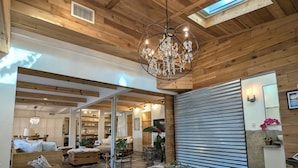 A spacious living area with a chandelier, wooden ceiling, and a large window. - Parkside INCREDIBLE location-VIEWS-Kayak, SUP, Pool, Gorgeous Hikes-Restaurants (Austin)