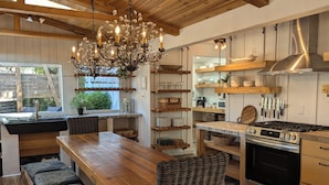 A kitchen with a wooden table, wicker chairs, a chandelier, and a stove. - Parkside INCREDIBLE location-VIEWS-Kayak, SUP, Pool, Gorgeous Hikes-Restaurants (Austin)
