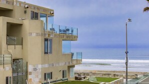 En moderne bygning med en glasbalkon med udsigt over stranden.