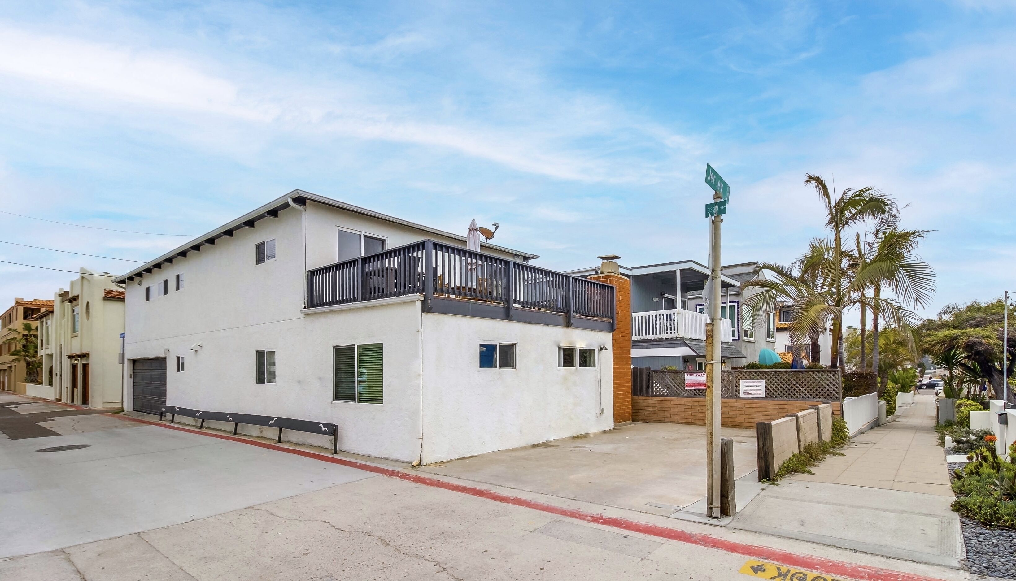 A two-story residential building with a balcony, a gated entrance, and a clear sky.