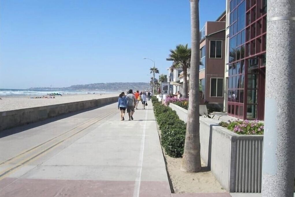 Un paseo marítimo junto a la costa, con una playa a un lado y edificios al otro.