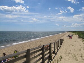 A beach with a wooden fence, sandy shore, and people relaxing. - Great SUMMER WEEKS Available! (New Seabury)