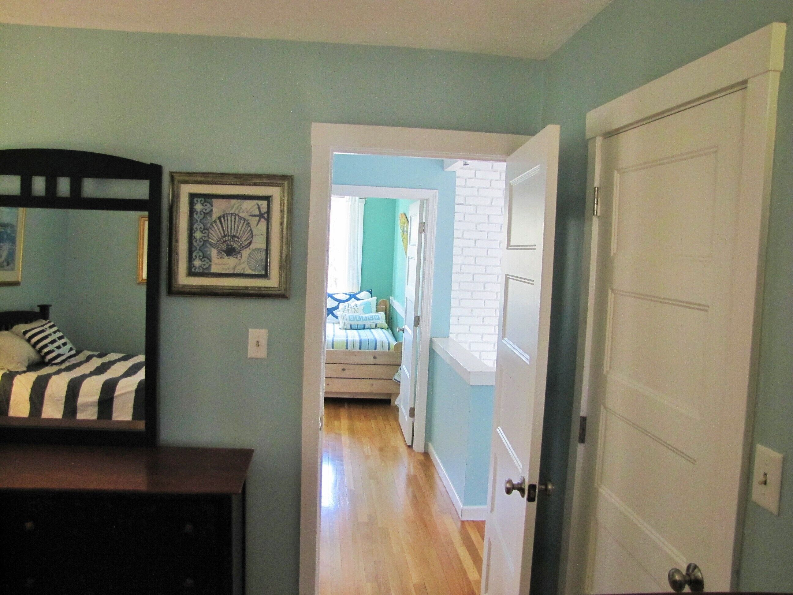 A bedroom with a bed, a dresser, and a framed picture on the wall.