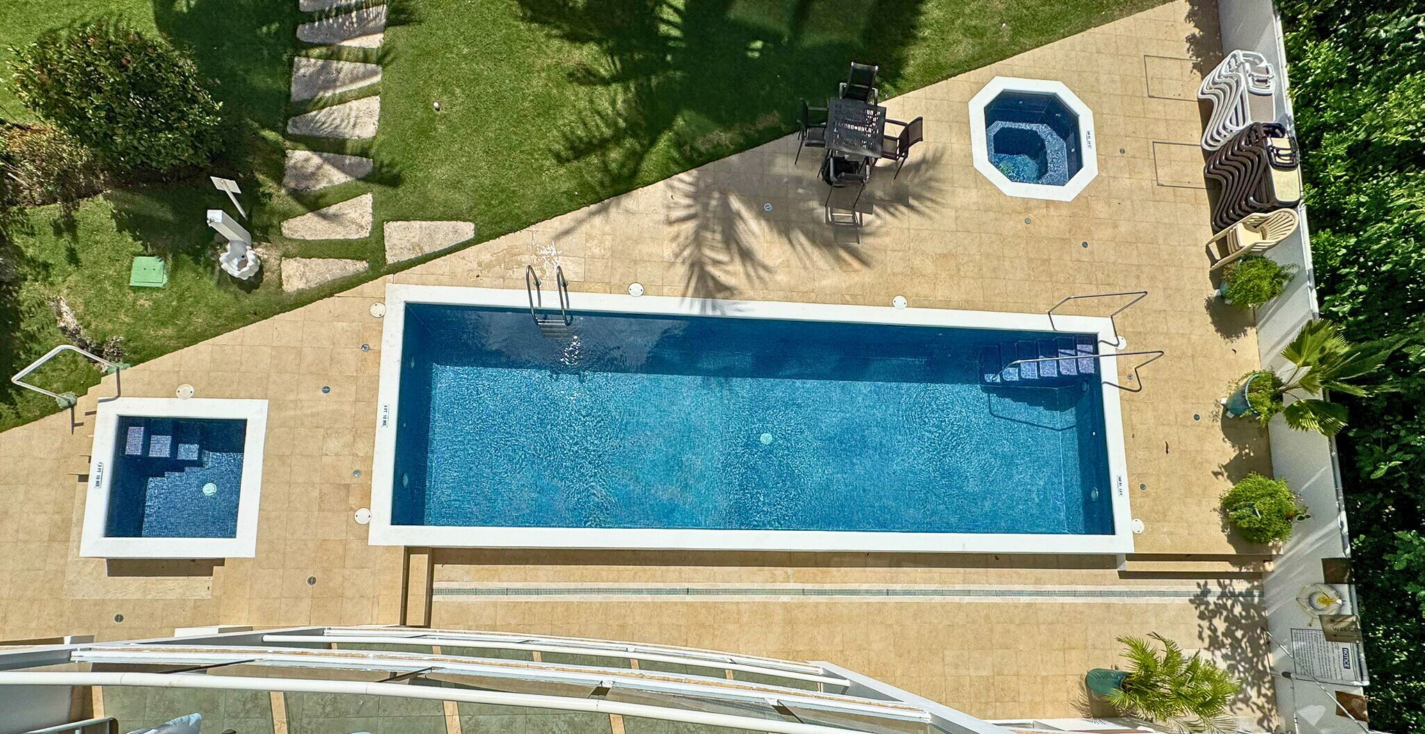 A rectangular swimming pool with a diving board, a smaller pool, and a hot tub.