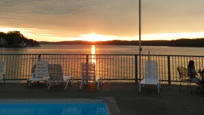 Vista del atardecer desde un área junto a la piscina con sillones de descanso y una bandera estadounidense.