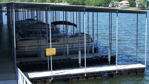 Un bote amarrado con una zona cubierta, un letrero de almacenamiento de combustible y una vista del agua y la vegetación al fondo.