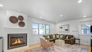 Una sala de estar moderna con chimenea, un sofá grande, una mesa de centro y una alfombra estampada.