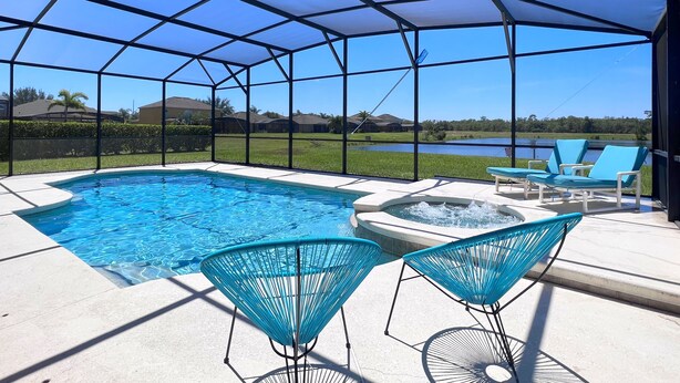 A covered outdoor swimming pool with a view of a lake and houses in the background. - LAKEVIEW from Your Private Pool! - Relax & Create Memories - Resort Near Disney! (Davenport)