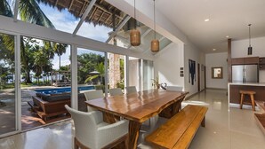 A modern kitchen with a large wooden table, wicker chairs, and a bench.