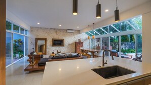 A modern kitchen with a large island, built-in appliances, and a dining area with a view of the outdoors.